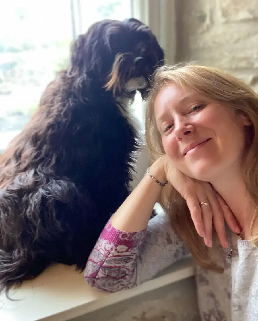 Melanie Phillips with Lily in their Welsh cottage Melanie Phillips smiling with her Tibetan Terrier, Lily, inside their cozy Welsh cottage.