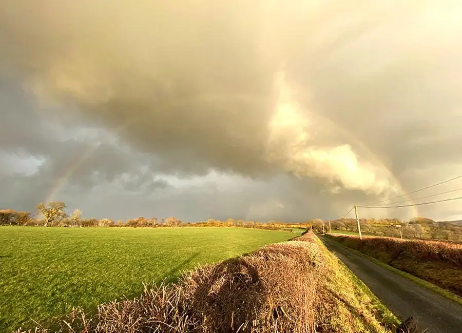 Sky and rainbow photography by Melanie A photograph taken by Melanie Phillips showcasing dramatic clouds and a vibrant rainbow across the sky.