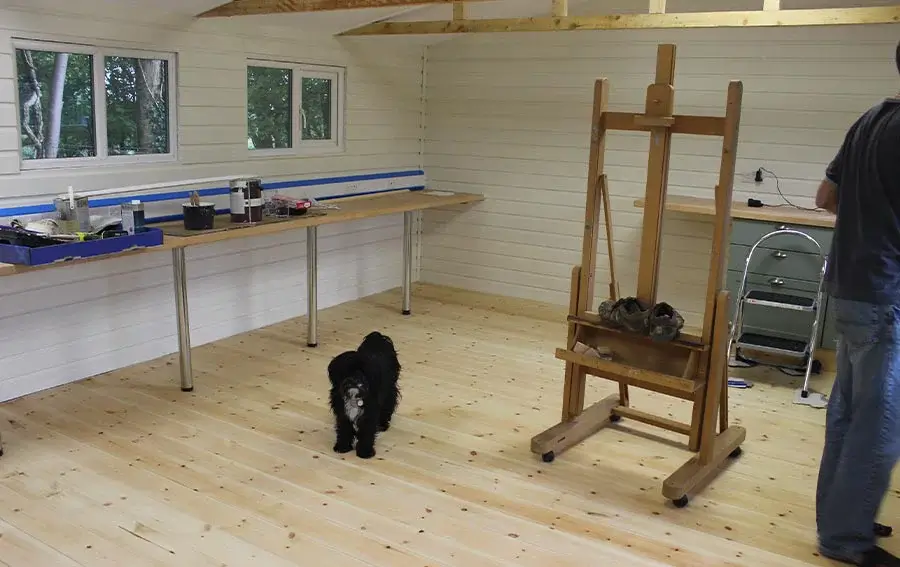 Undercoat, Floor Varnish, and Kitchen Area in Progress Interior shot of the studio renovation showing painted undercoat on walls, varnished floorboards, and the early stages of fitting the kitchen area.