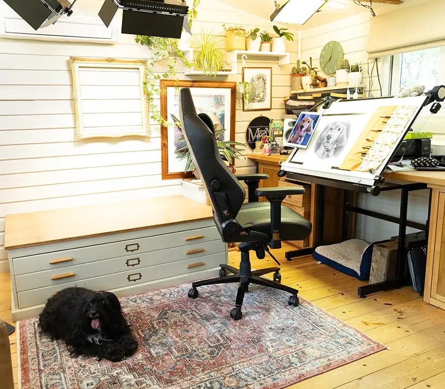 Melanie's Dedicated Studio Workspace for Pencil Drawings Melanie's organized drawing desk inside the art studio, featuring a tilted drawing board, laptop, and monitor setup for pencil portraits.